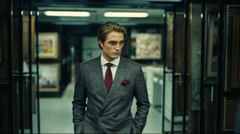 Movie still from “Tenet” (2020), directed by Christopher Nolan – A man in a suit and tie standing in a room; Medium shot, Low angle
