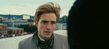 Movie still from “Tenet” (2020), directed by Christopher Nolan – A person wearing a suit and tie; Close Up shot, Over the shoulder angle