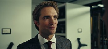 Movie still from “Tenet” (2020), directed by Christopher Nolan – A person wearing a suit and tie; Close Up shot, Over the shoulder angle