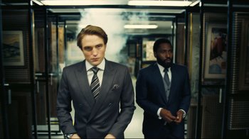 Movie still from “Tenet” (2020), directed by Christopher Nolan – A man in a suit standing next to another man in a suit; Medium shot, Low angle