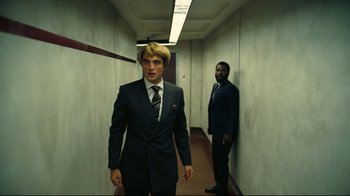 Movie still from “Tenet” (2020), directed by Christopher Nolan – A man in a suit and tie standing next to another man in a suit and tie; Medium shot, Low angle