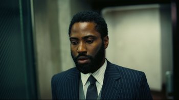 Movie still from “Tenet” (2020), directed by Christopher Nolan – A man in a suit and tie looking down; Close Up shot, Low angle