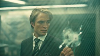 Movie still from “Tenet” (2020), directed by Christopher Nolan – A man in a suit and tie holding a cigarette; Close Up shot, Over the shoulder angle