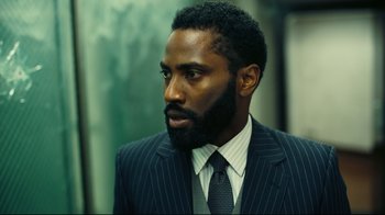 Movie still from “Tenet” (2020), directed by Christopher Nolan – A man in a suit and tie looking to his left; Close Up shot, Low angle