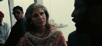 Movie still from “Tenet” (2020), directed by Christopher Nolan – An older woman with long gray hair wearing a scarf; Close Up shot, Over the shoulder angle