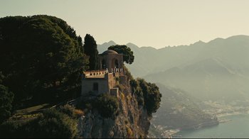 Movie still from “Tenet” (2020), directed by Christopher Nolan – A building on top of a cliff overlooking the ocean; Extreme Wide shot, Low angle