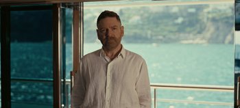 Movie still from “Tenet” (2020), directed by Christopher Nolan – A man standing in front of a large window; Medium shot, Over the shoulder angle