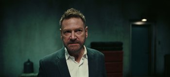 Movie still from “Tenet” (2020), directed by Christopher Nolan – A person wearing a suit and tie; Close Up shot, Over the shoulder angle