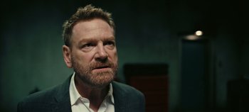 Movie still from “Tenet” (2020), directed by Christopher Nolan – A person wearing a suit and tie; Close Up shot, Over the shoulder angle