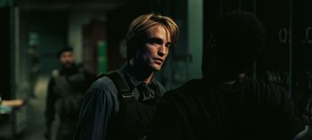 Movie still from “Tenet” (2020), directed by Christopher Nolan – A person wearing a suit and tie; Close Up shot, Over the shoulder angle