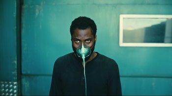 Movie still from “Tenet” (2020), directed by Christopher Nolan – A man with a gas mask on his face; Medium shot, Overhead angle