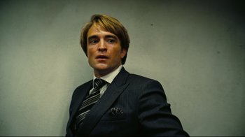 Movie still from “Tenet” (2020), directed by Christopher Nolan – A person wearing a suit and tie; Close Up shot, Low angle