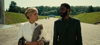 Movie still from “Tenet” (2020), directed by Christopher Nolan – A man and a woman standing next to each other on a sidewalk; Medium shot, Low angle