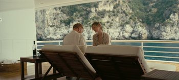 Movie still from “Tenet” (2020), directed by Christopher Nolan – A man and a woman sitting at a table on a boat; Medium shot, Over the shoulder angle