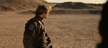 Movie still from “Tenet” (2020), directed by Christopher Nolan – A man in a military uniform standing in the desert; Medium shot, Over the shoulder angle