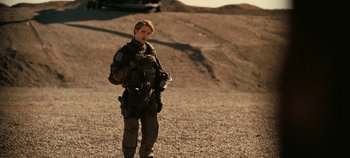 Movie still from “Tenet” (2020), directed by Christopher Nolan – A man standing on a dirt road holding a camera; Medium shot, Low angle