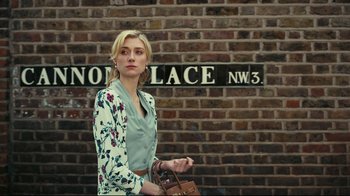 Movie still from “Tenet” (2020), directed by Christopher Nolan – A beautiful blonde woman holding a brown purse; Medium shot, Over the shoulder angle