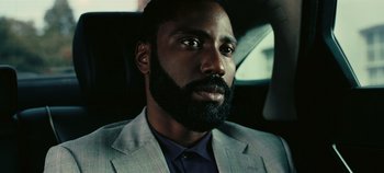 Movie still from “Tenet” (2020), directed by Christopher Nolan – A man in a suit and tie in the back of a car; Close Up shot, Low angle