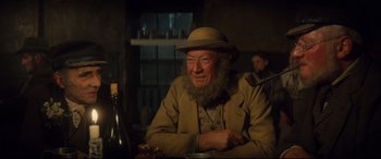 Movie still from “Tess” (1979), directed by Roman Polanski – An old man sitting at a table with a bottle of wine in front of him; Close Up shot, Low angle