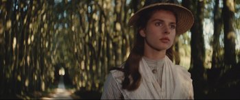 Movie still from “Tess” (1979), directed by Roman Polanski – A young woman wearing a hat in front of a forest; Close Up shot, Low angle