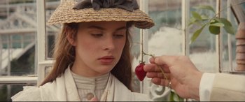 Movie still from “Tess” (1979), directed by Roman Polanski – A woman wearing a straw hat holding a red pepper; Close Up shot, Over the shoulder angle