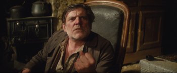 Movie still from “Tess” (1979), directed by Roman Polanski – A man sitting in a chair with his finger pointed at the camera; Medium shot, Low angle