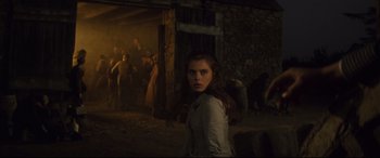 Movie still from “Tess” (1979), directed by Roman Polanski – A woman standing in front of a group of people in the dark; Wide shot, Over the shoulder angle