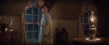 Movie still from “Tess” (1979), directed by Roman Polanski – A woman in a white dress standing in front of a window; Medium shot, Over the shoulder angle