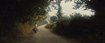 Movie still from “Tess” (1979), directed by Roman Polanski – A woman walking down a dirt road holding a basket; Extreme Wide shot, High angle