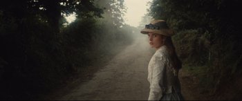 Movie still from “Tess” (1979), directed by Roman Polanski – A woman in a straw hat standing on the side of a dirt road; Medium shot, Low angle