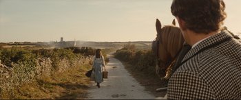 Movie still from “Tess” (1979), directed by Roman Polanski – A woman walking down a dirt road with two suitcases and a horse; Wide shot, Over the shoulder angle