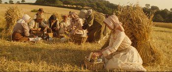 Movie still from “Tess” (1979), directed by Roman Polanski – A group of people sitting in a field with baskets of food; Wide shot, High angle
