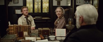 Movie still from “Tess” (1979), directed by Roman Polanski – An older woman sitting at a table in front of books; Medium shot, High angle