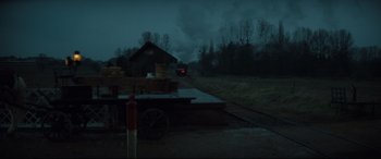 Movie still from “Tess” (1979), directed by Roman Polanski – A train traveling down train tracks next to a train station; Extreme Wide shot, Low angle