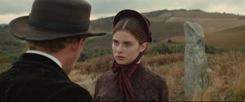 Movie still from “Tess” (1979), directed by Roman Polanski – A woman in a hat and a dress standing next to a man in a field; Close Up shot, Over the shoulder angle