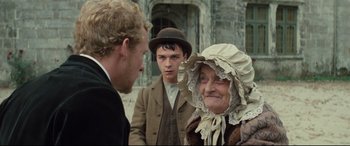 Movie still from “Tess” (1979), directed by Roman Polanski – A man and a woman talking to another man in front of a building; Medium shot, Over the shoulder angle