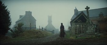 Movie still from “Tess” (1979), directed by Roman Polanski – An old woman walking down a dirt road in the fog; Extreme Wide shot, Low angle