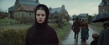 Movie still from “Tess” (1979), directed by Roman Polanski – A young woman in a hooded scarf walking down a road; Close Up shot, Over the shoulder angle