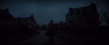 Movie still from “Tess” (1979), directed by Roman Polanski – A man with a hat and a bag walking down a street; Extreme Wide shot, Low angle