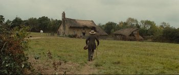 Movie still from “Tess” (1979), directed by Roman Polanski – A man walking in a field near a house; Extreme Wide shot, High angle