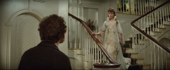 Movie still from “Tess” (1979), directed by Roman Polanski – A woman in a dress standing next to a railing; Medium shot, Over the shoulder angle
