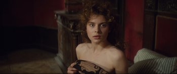 Movie still from “Tess” (1979), directed by Roman Polanski – A woman with curly red hair holding a brown bag; Close Up shot, Over the shoulder angle