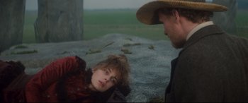 Movie still from “Tess” (1979), directed by Roman Polanski – A man and a woman are sitting on the ground in a field; Medium shot, Over the shoulder angle