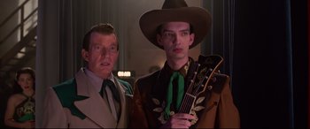 Movie still from “Elvis” (2022), directed by Baz Luhrmann – A man holding a guitar and another man standing next to him; Close Up shot, Low angle