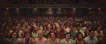 Movie still from “Elvis” (2022), directed by Baz Luhrmann – A large group of people sitting in a large auditorium; Wide shot, High angle