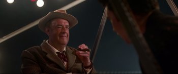 Movie still from “Elvis” (2022), directed by Baz Luhrmann – An older man wearing a suit and hat holding a sword; Close Up shot, Over the shoulder angle