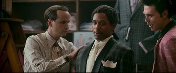 Movie still from “Elvis” (2022), directed by Baz Luhrmann – A man in a suit and tie is being fitted by another man in a suit and tie; Close Up shot, Over the shoulder angle