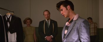 Movie still from “Elvis” (2022), directed by Baz Luhrmann – A man in a suit standing next to another man in a suit; Medium shot, Over the shoulder angle