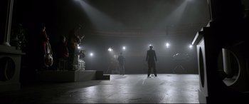 Movie still from “Elvis” (2022), directed by Baz Luhrmann – A group of people standing on a stage with lights on; Extreme Wide shot, Low angle