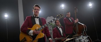 Movie still from “Elvis” (2022), directed by Baz Luhrmann – A group of men standing next to each other holding guitars; Medium shot, Low angle